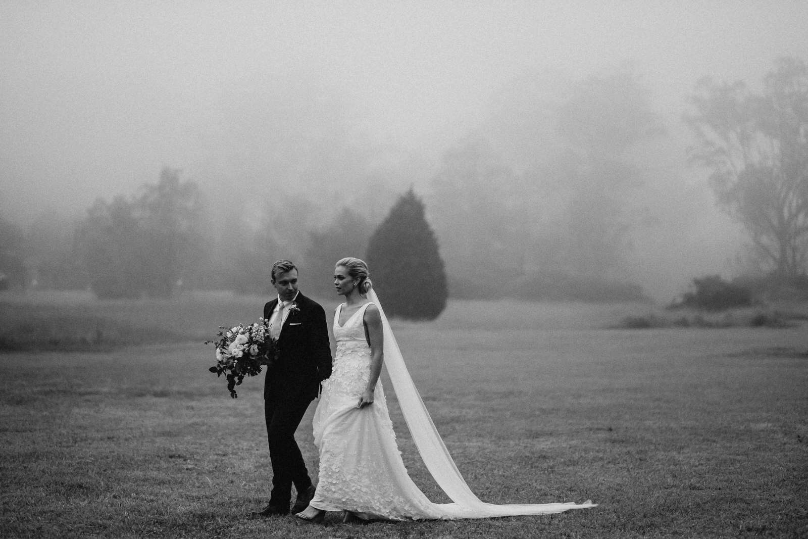Toowoomba Wedding Photographer, couple walking in thick fog of Toowoomba across field.