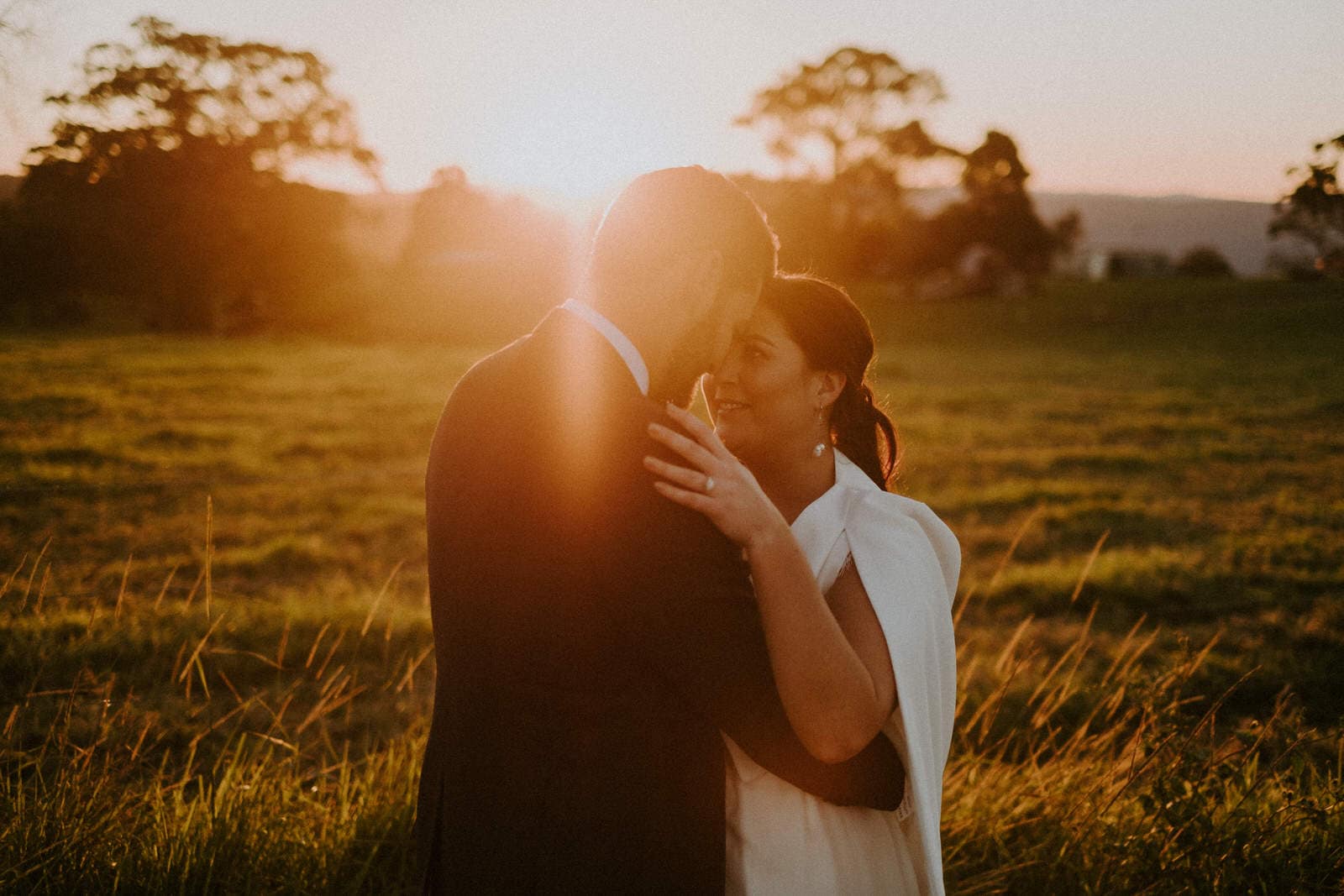 Sunshine Coast wedding photographer, Bride and groom embracing at sunset with golden light backlighting the couple after their ceremony at Maleny Retreat.