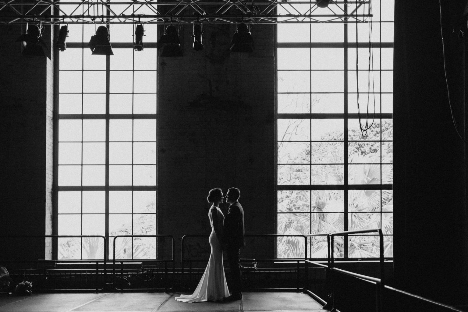 Couple standing in front of large windows for their Brisbane Power House wedding.