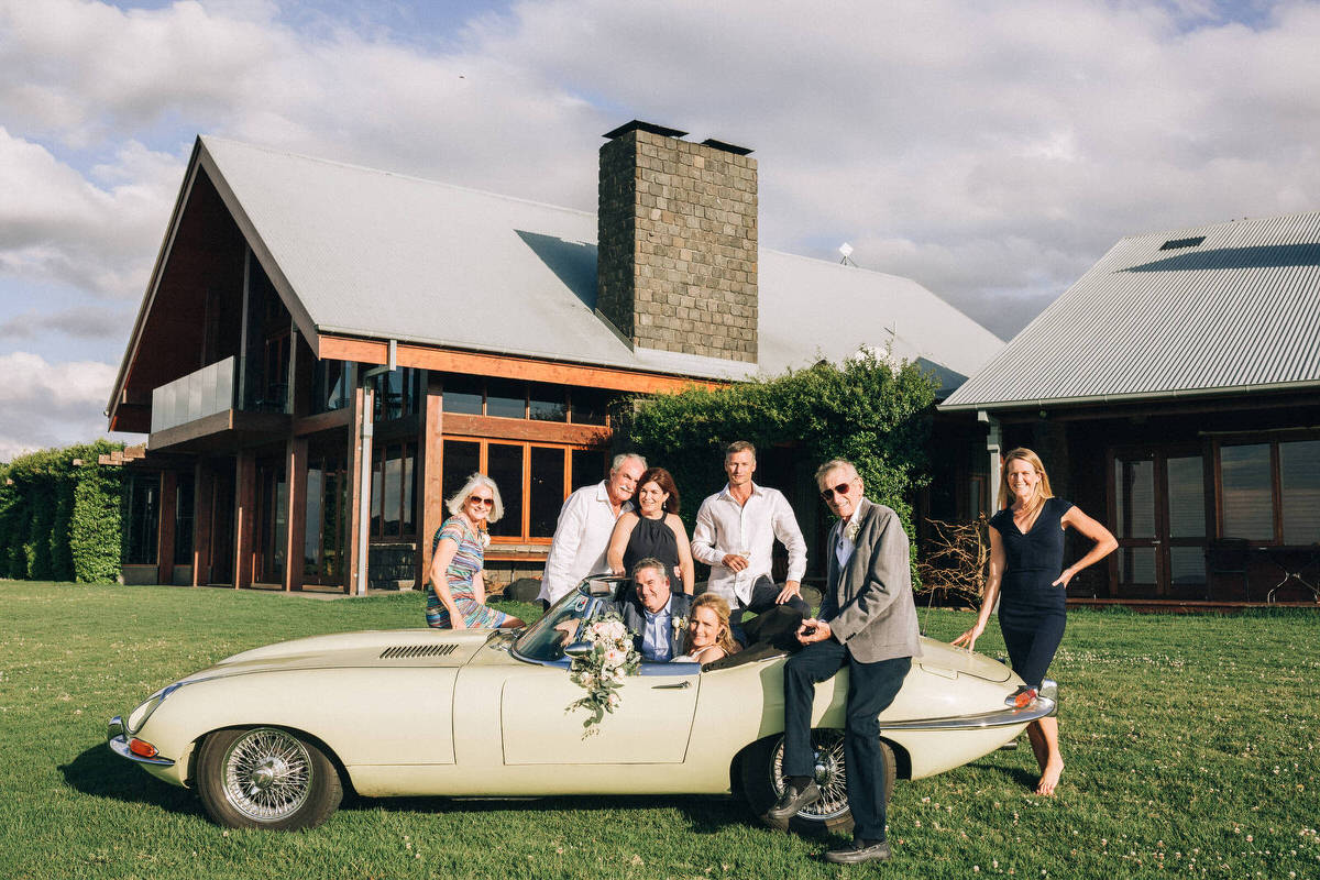 Intimate elopement with their guests crowded around vintage E type jaguar infant of Spicers Peak Lodge
